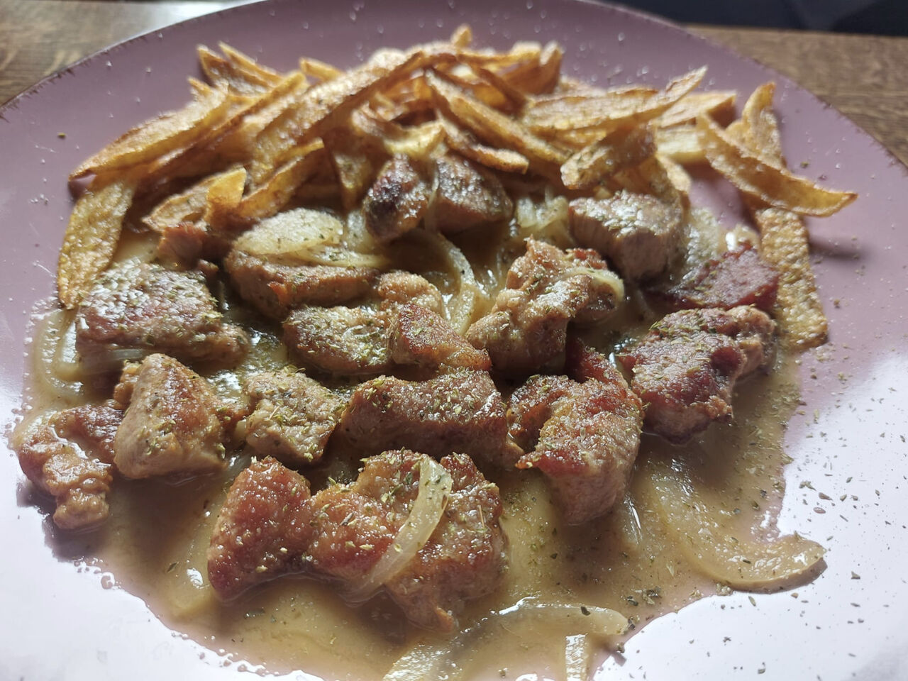 Tigania - gebratene Schweinefleisch Stücke in der Pfanne mit Zwiebeln, Wein, Zitrone & Salat