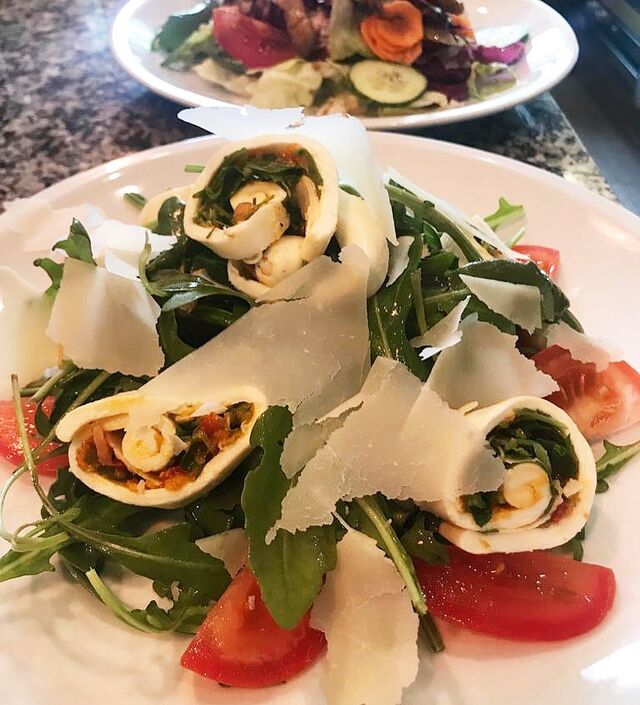 Mozzarellarollen auf Rucolasalat und Tomaten
