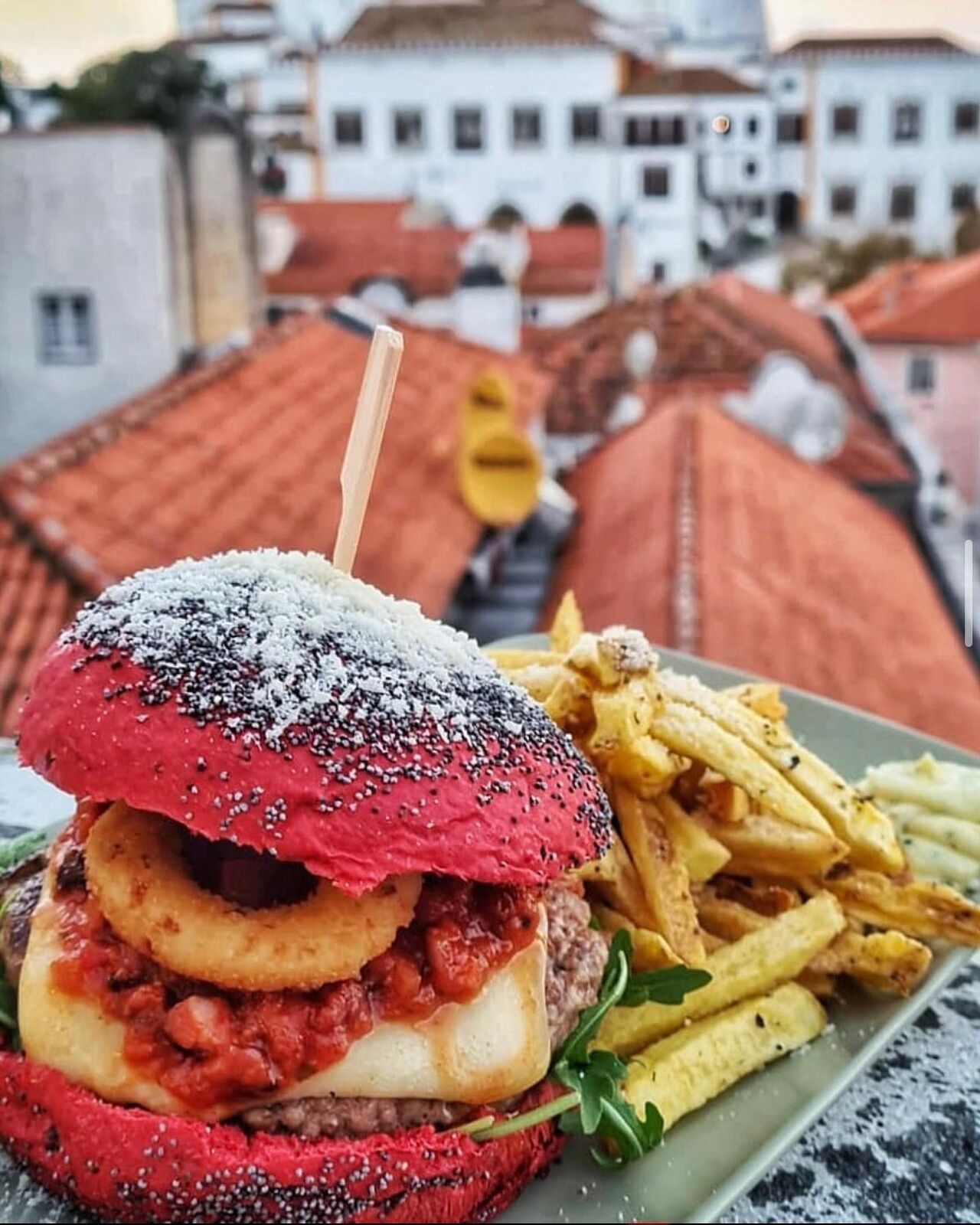 Hambúrguer da Ferraria com pão vermelho, batatas e os telhados de Sintra ao fundo