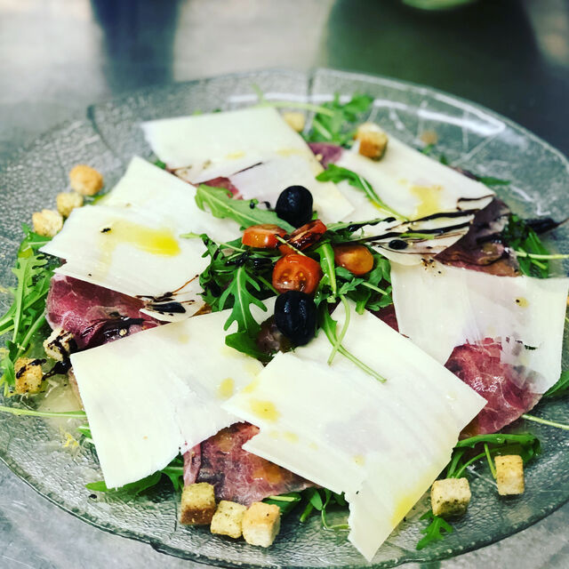 Rindercarpaccio auf rucola mit frische Champignons e Parmesan Blätter.