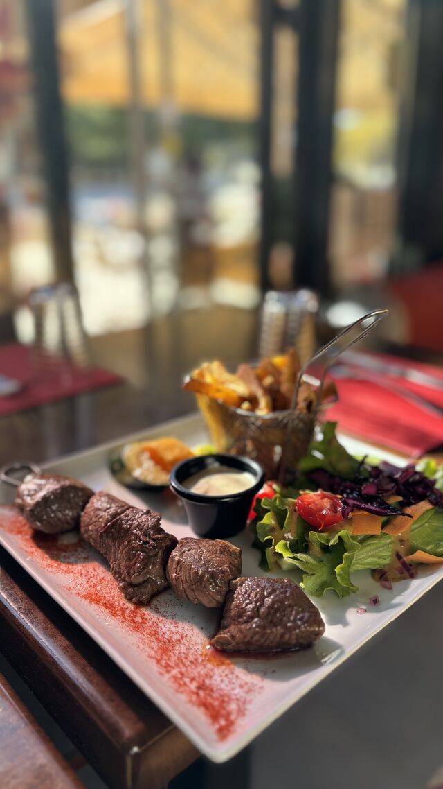 Brochette de boeuf, sauce maison, frites maison, légumes et salade 