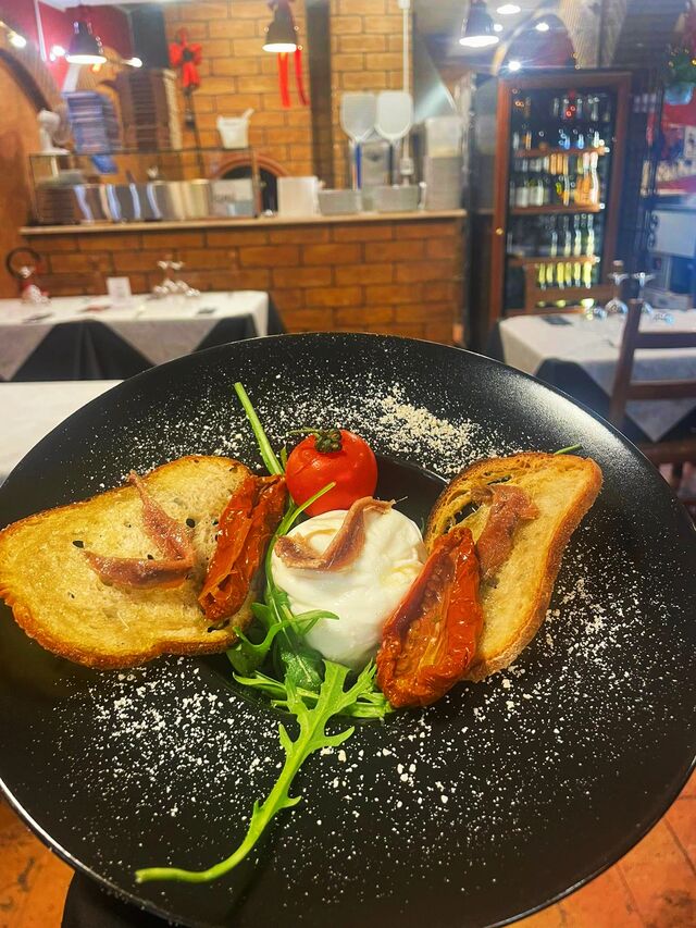 Burratina con alici del Cantabrico, pomodori secchi, tegole di pane croccante e crumble di taralli