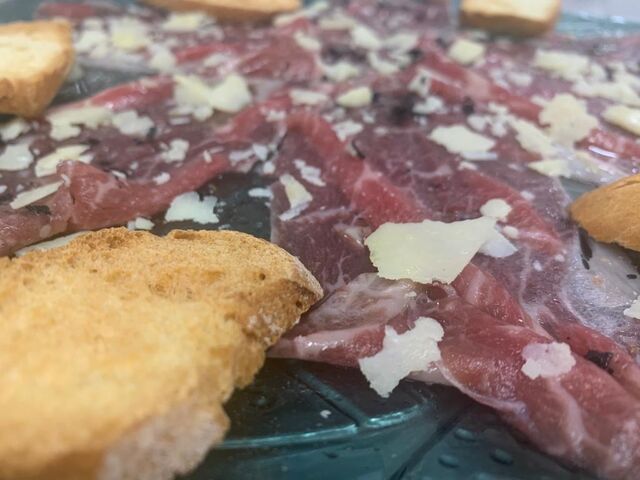 Carpaccio de chuleta de vaca, con parmesano, escama de sal negra, pan tostado y aceite de trufa negra.