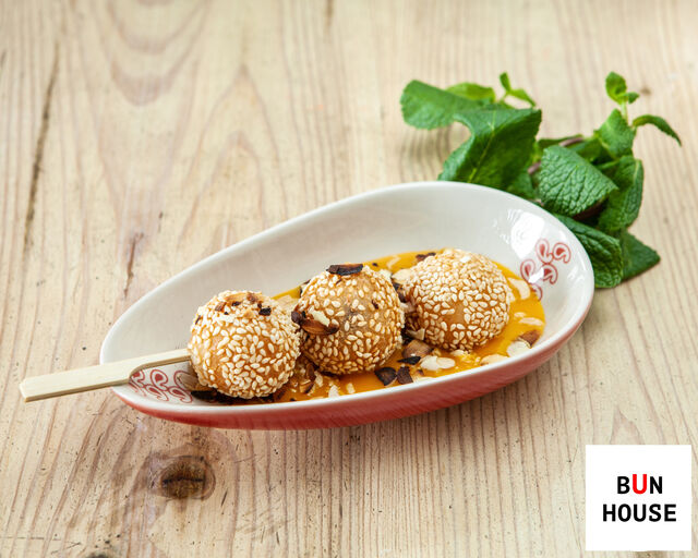 Słodkie chińskie kulki sezamowe z nadzieniem z pasty z czerwonej fasoli, podane na pulpie mango i prażonych migdałach