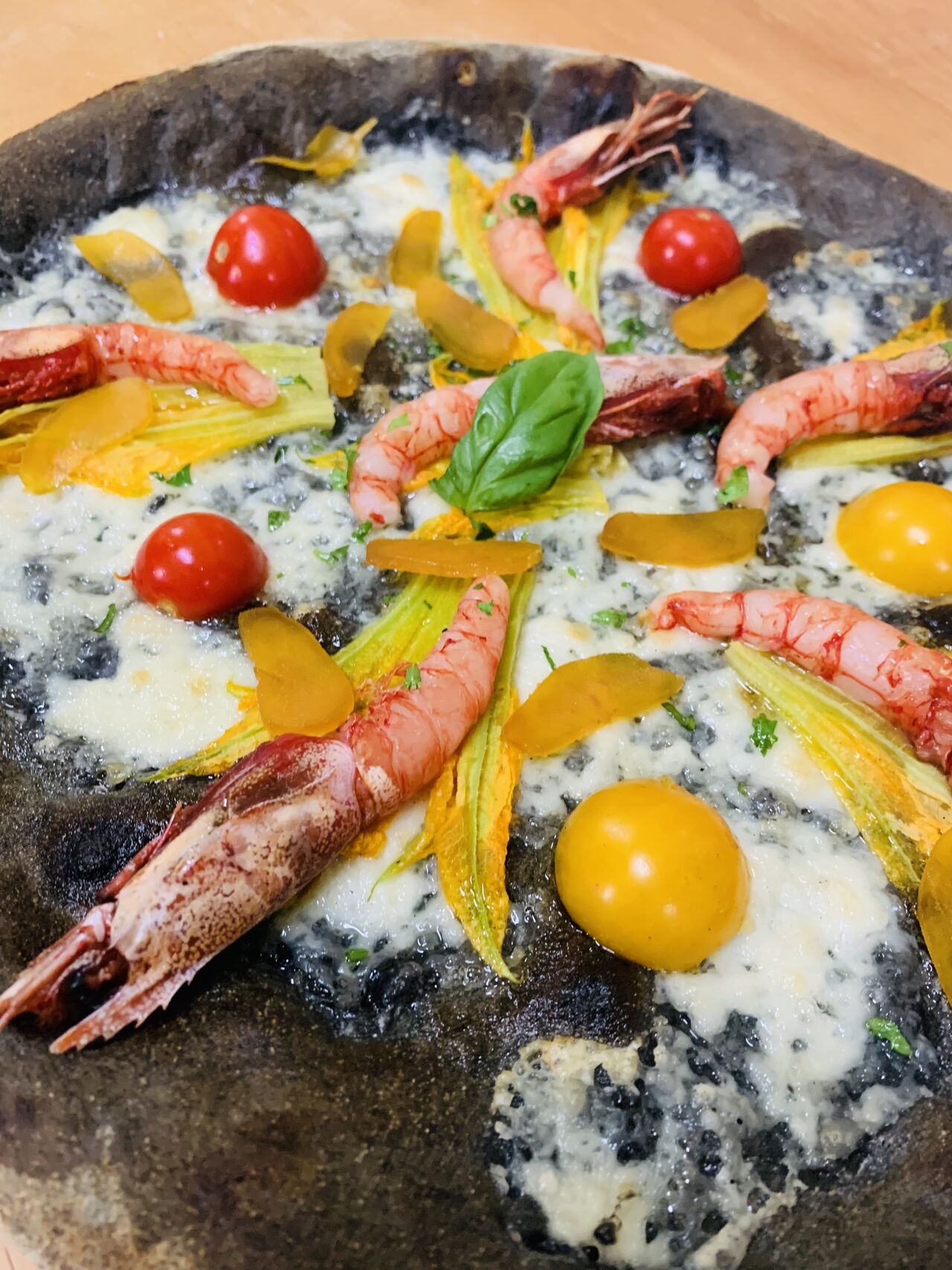 Impasto al carbone vegetale con gamberi sgusciati, fiori di zucca, bottarga a scaglie e pomodorini colorati