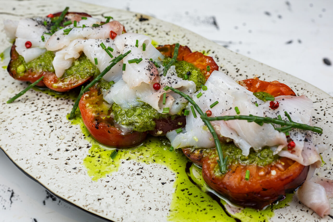 🍅 Tomate a la brasa, pesto, queso parmesano 🧀 y carpaccio de serviola 🐠 con su piel crujiente.