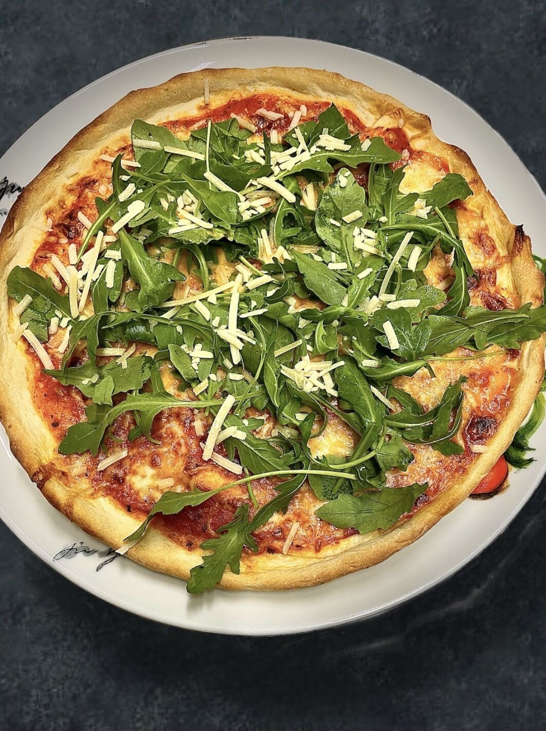 Probieren Sie einen Klassiker der italienischen Küche - unsere herzhafte Rucola-Pizza mit frisch gehobelten Parmigiano! 