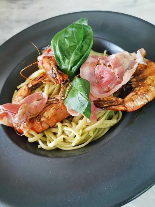 Linguines au pesto, gambas flambées et pancetta grillés. 