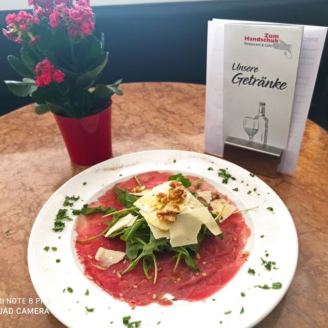 Rindfleisch-Carpaccio mit Rucola, Parmesanflocken, gehackten Walnüssen und Zitrone