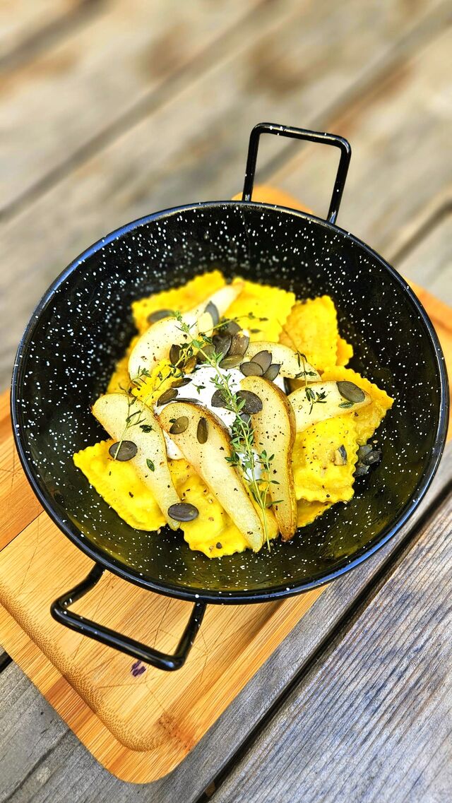 Sezonowe ravioli z kaczką, gruszką karmelizowaną na maśle z tymiankiem, burratą, kaparami i pestkami dyni.