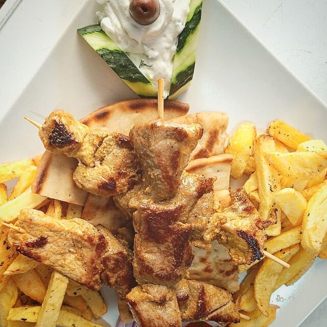 Kalamaki jirinó: 3 brochetas de cerdo marinado con tzatziki, tomate, patatas fritas caseras y pita.