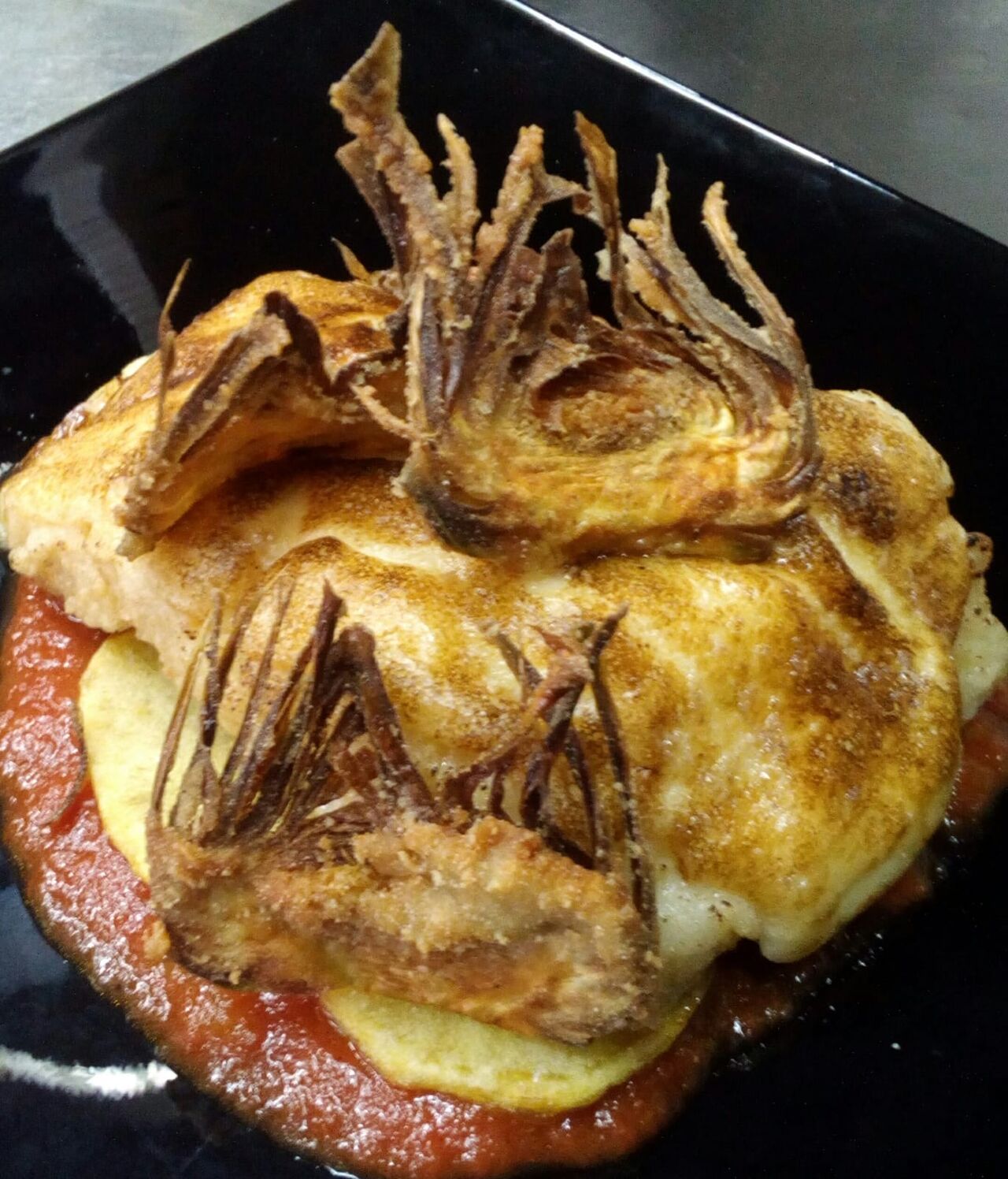 Merluza con alioli gratinada, acompañada por chips de alcachofas
