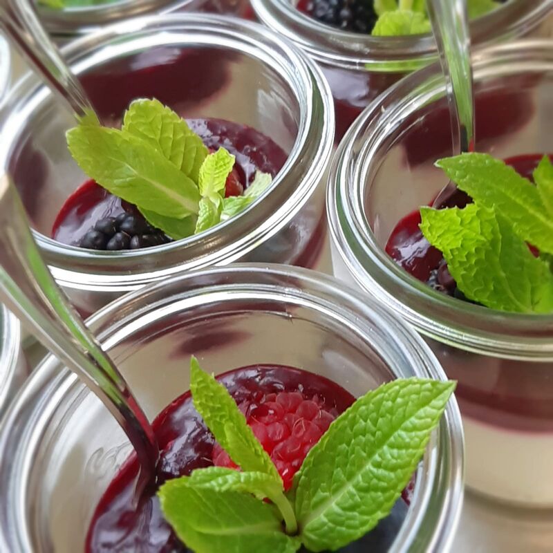Ein sahniger Nachtisch im Glas, darauf eine fruchtige Schicht aus frischen Waldfrüchten
