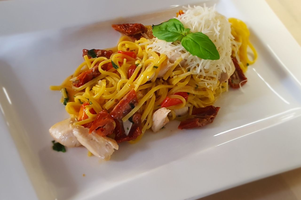 Domácí tagliatelle s kuřecím masem a sušenými rajčaty sypané parmazánem