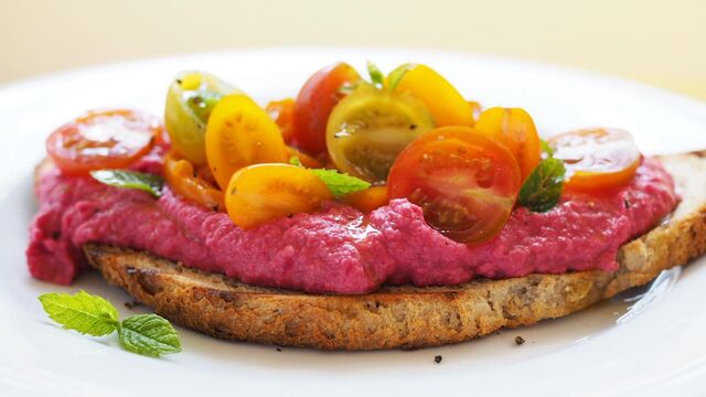 Vegan beetroot hummus toast with slow cooked peppers, cherry tomatoes and mint
