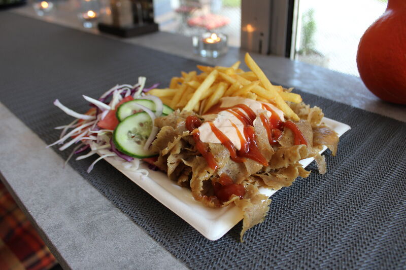 Wersja obiadowa: mięso, frytki, warzywa i sos podane na talerzu.