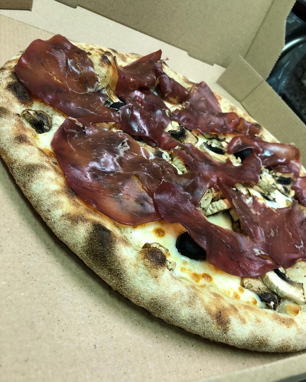 Pizza base crème de truffe, mozzarella, champignons, bresola (boeuf séché) 