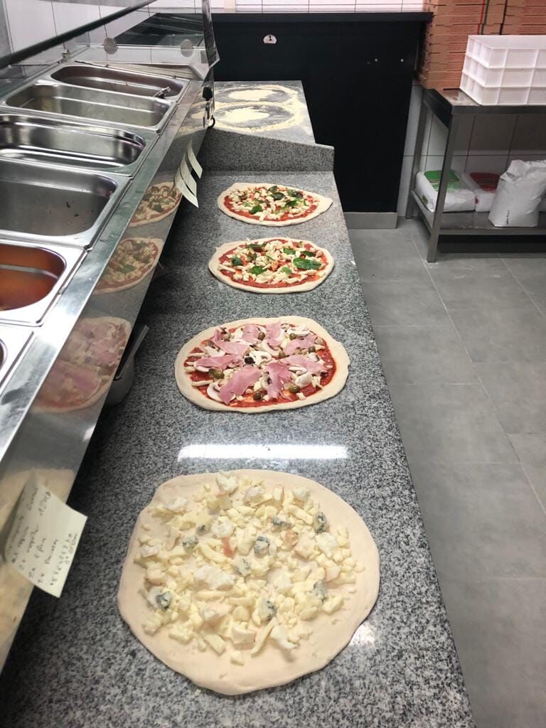 Garnissage des pizzas avec des produits italiens de qualité