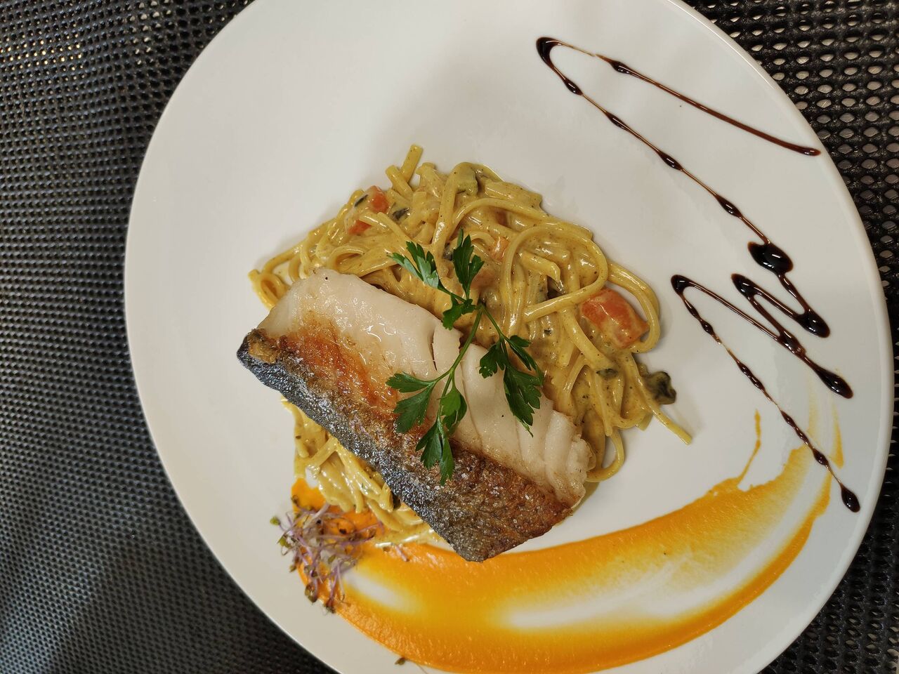 Dos de cabillaud rôti, crème de curry aux petits légumes et linguines.