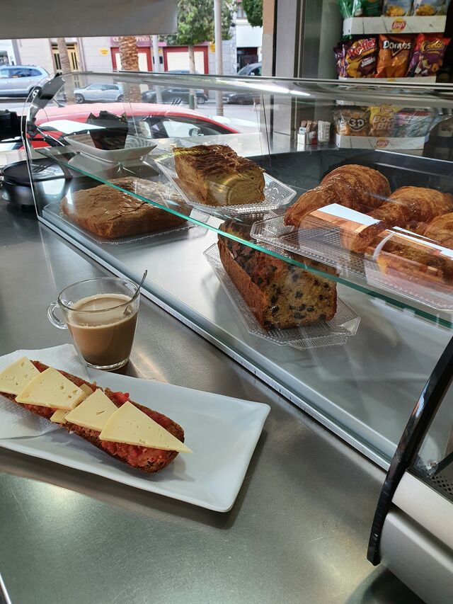 Tostada integral con tomate y queso, junto con la bollería para desayunar también