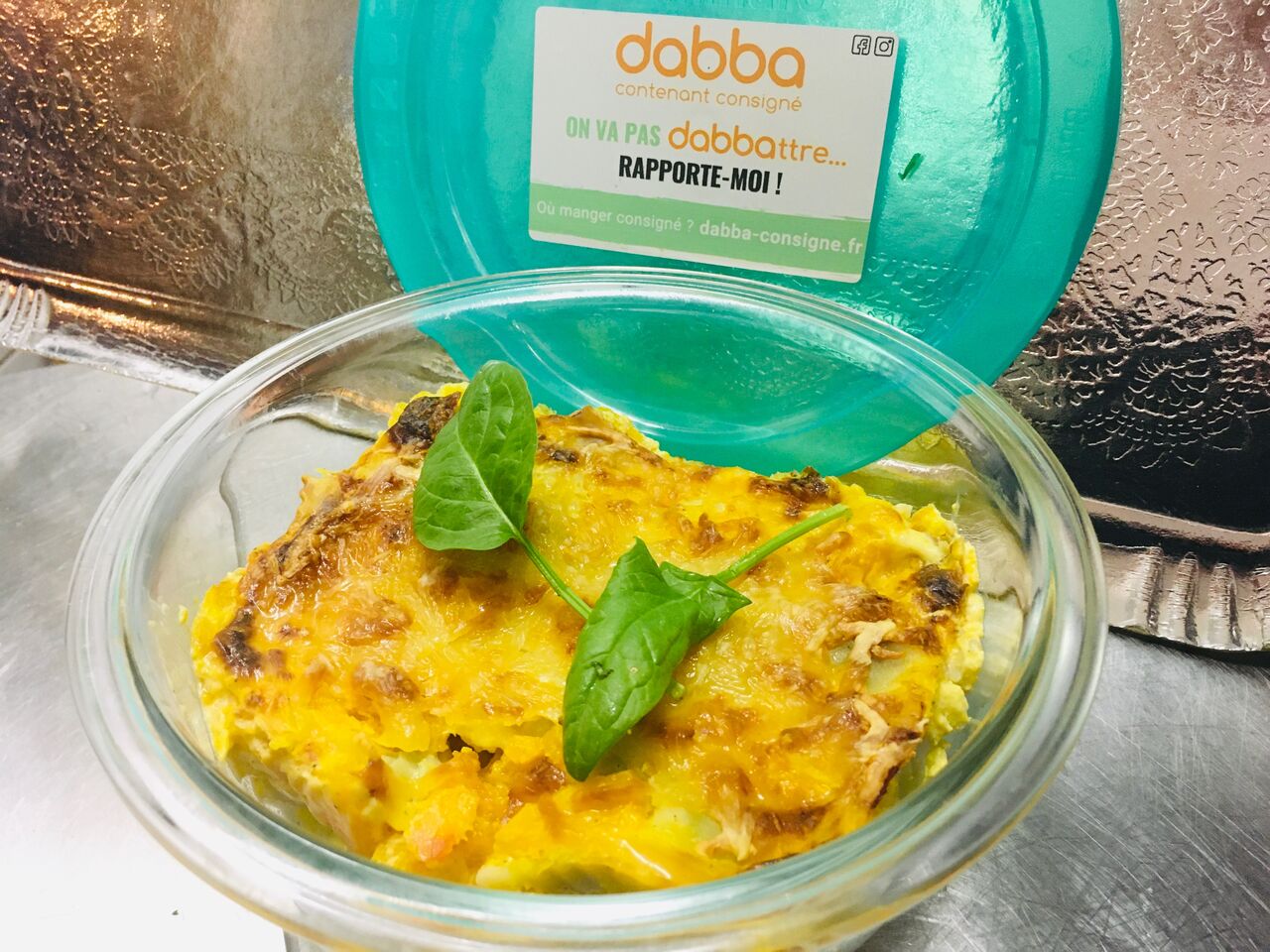 Gratin de ravioles-potimarron servi dans un récipient en verre dabba consigné.