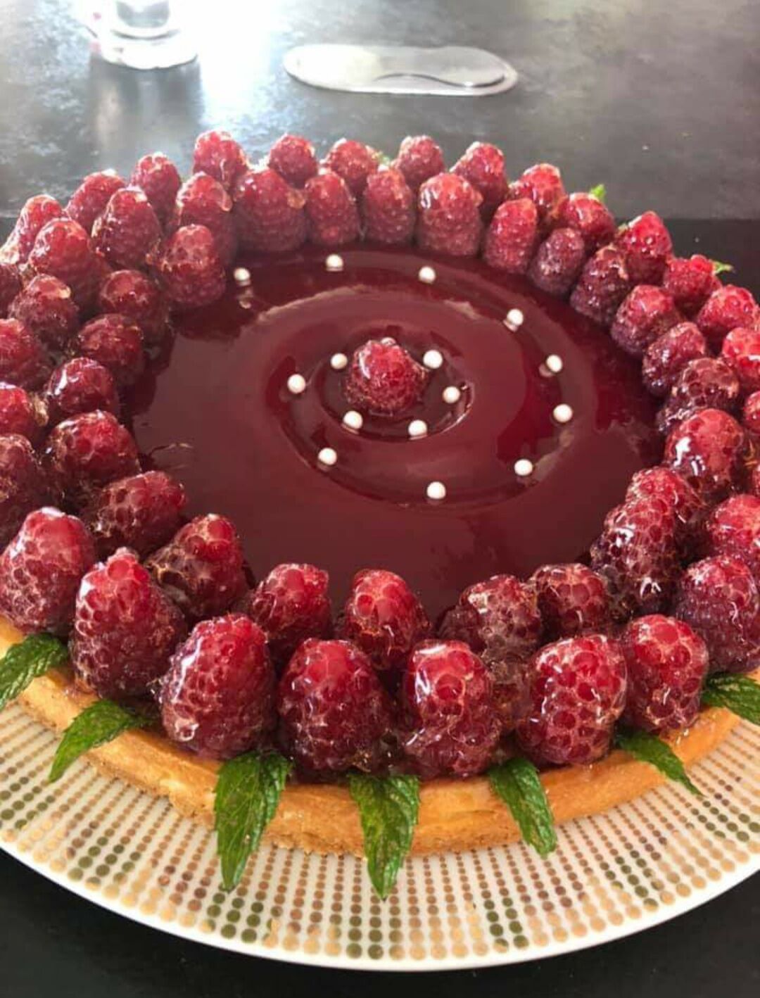 Tarte aux fruits rouges avec un sablé , une crème d'amandes une gelée de framboises et framboises , quelques feuilles de menthe.