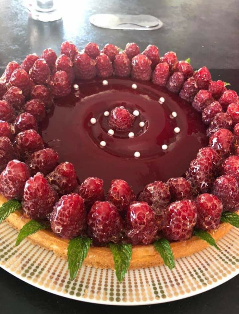 Tarte aux fruits rouges avec un sablé , une crème d'amandes une gelée de framboises et framboises , quelques feuilles de menthe.