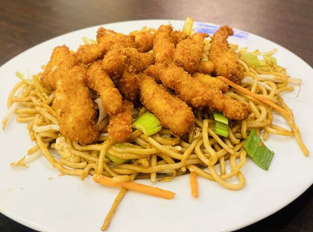 Knusprige Chicken-Sticks auf gebratene Nudeln mit Gemüse und Ei, dazu süß-saure Sauce