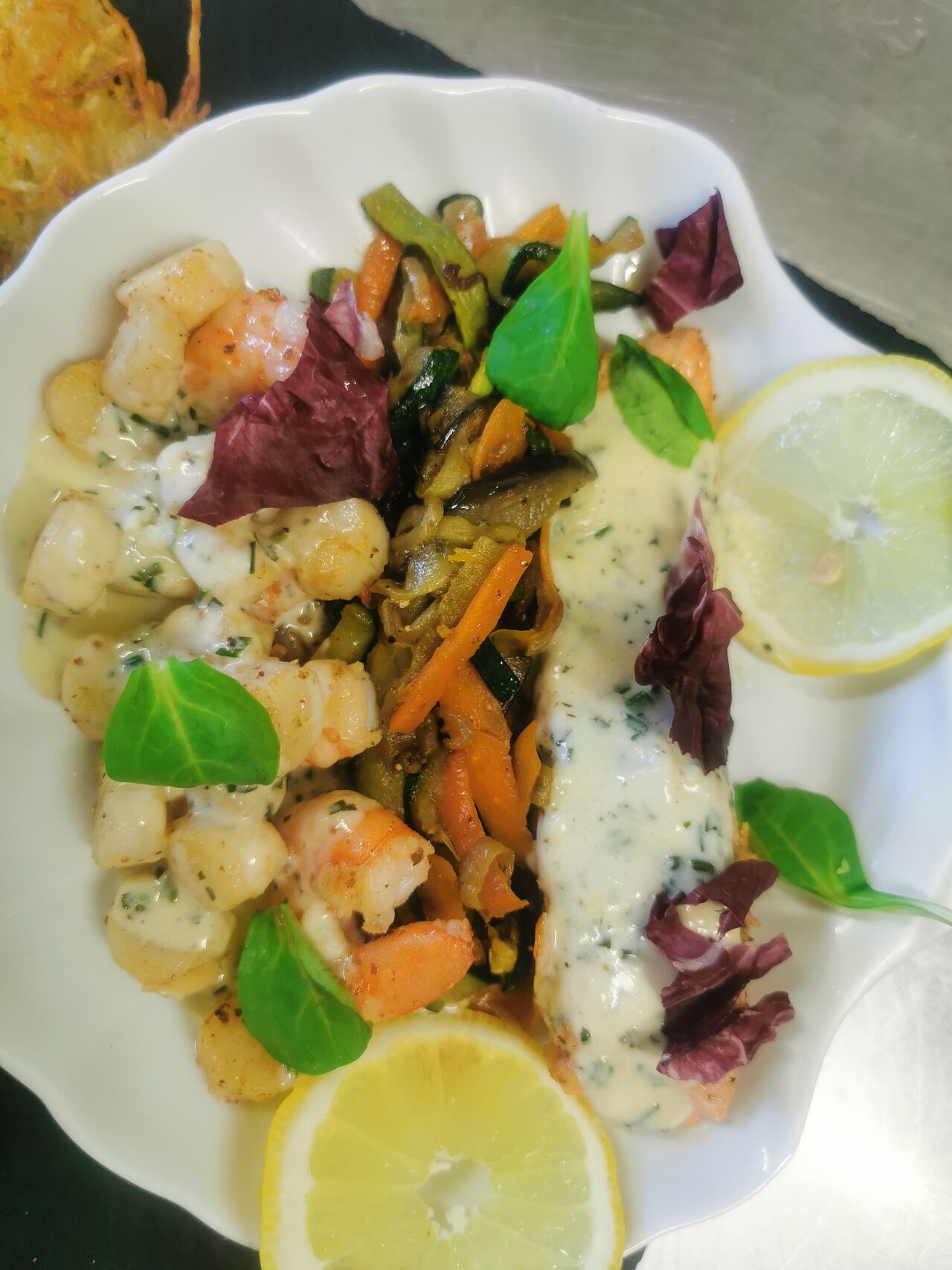 Le pavé de saumon et scampis noix de st jacques sur lit de légumes du soleil sauce ail citronné. 