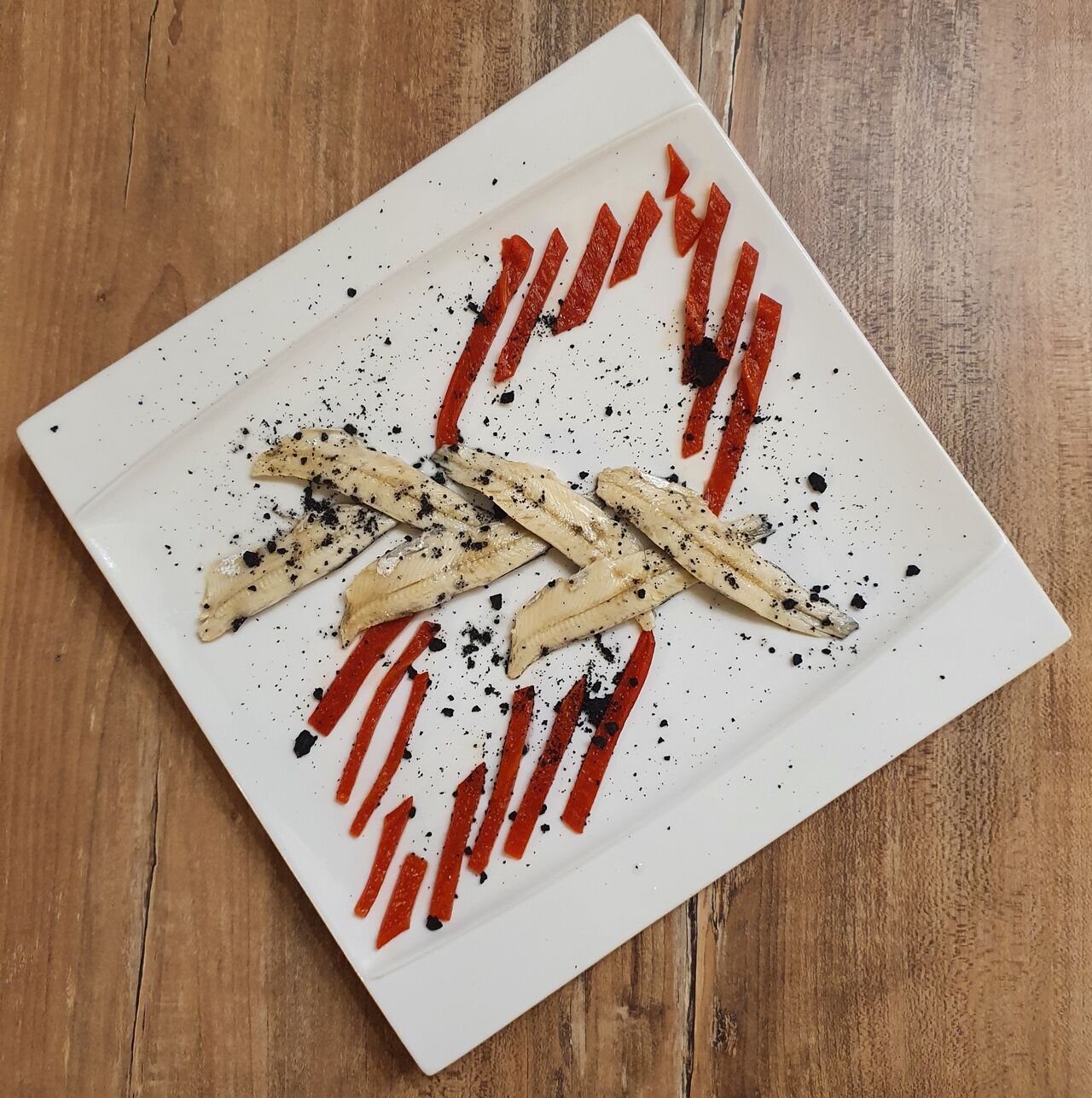 Anchois et piquillos, crumble à l'encre de seiche 