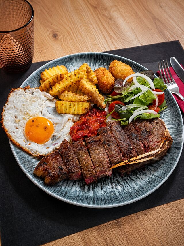nuestro plato del día chuleta ración ensalada pimiento rojos asados croquetas de jamón patatas y huevo frito