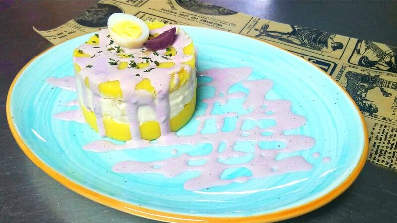 Causa Limeña:
Papa prensada y aderezada con limas y ajíes, rellena con ensalada de Pollo, bañada en salsa de Aceituna Botija.