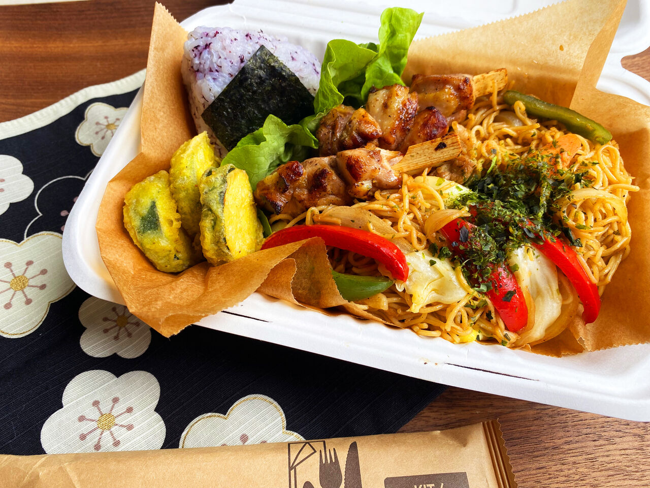Obento: yakisoba, brochettes de poulet, frites de courgettes, onigiri au shiso rouge