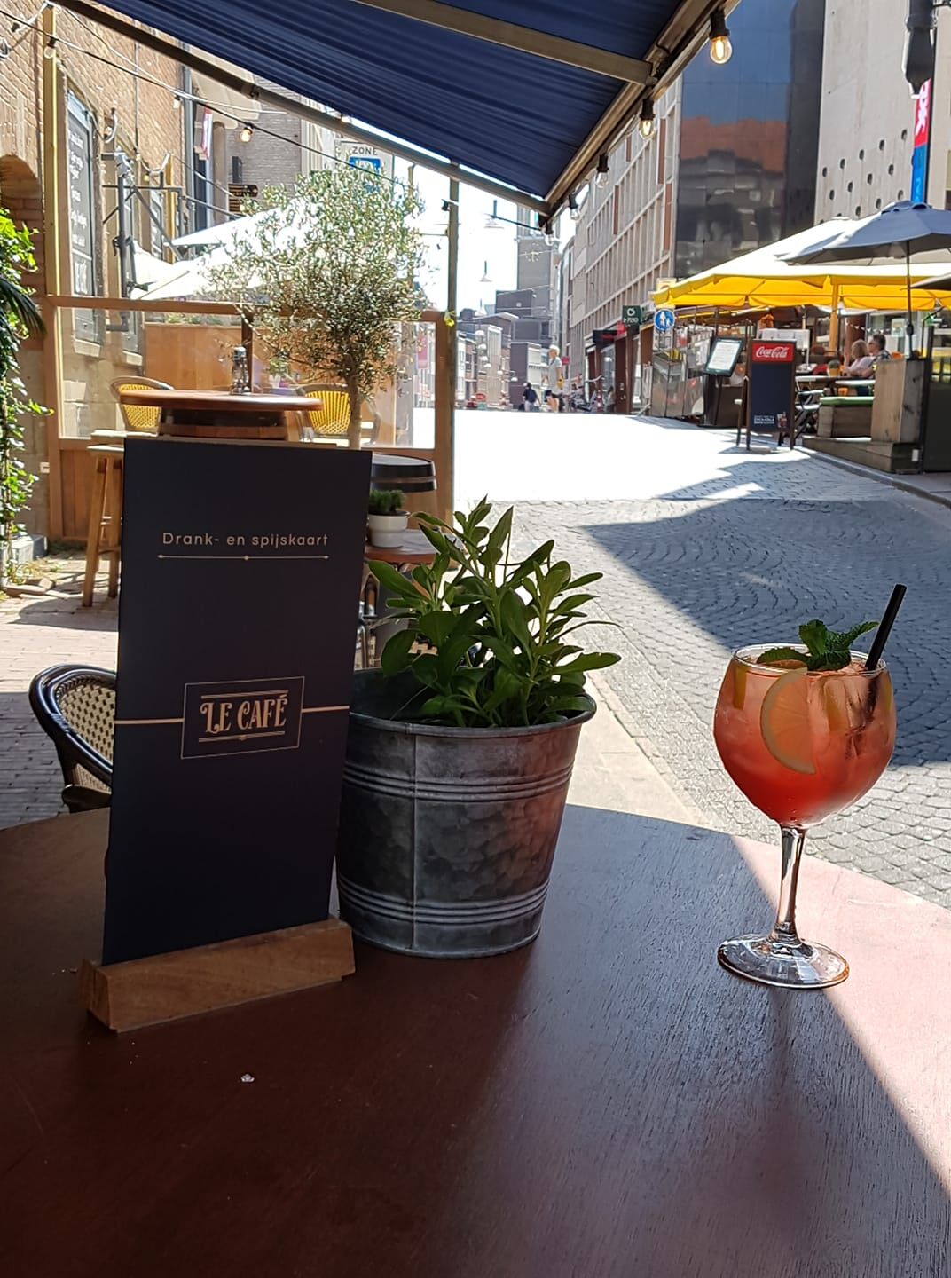 src=https://cdn.website.dish.co/media/d9/1e/3118702/Le-Cafe-foto-terras.jpg