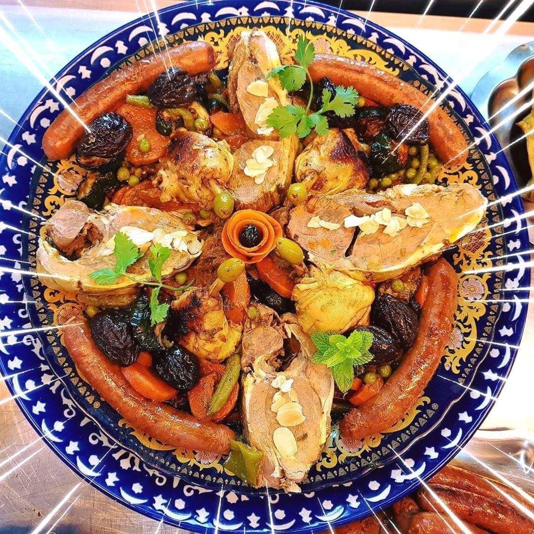Un tajine de légumes et pruneaux accompagné de tranches d'épaule d 'agneau méchoui et merguez