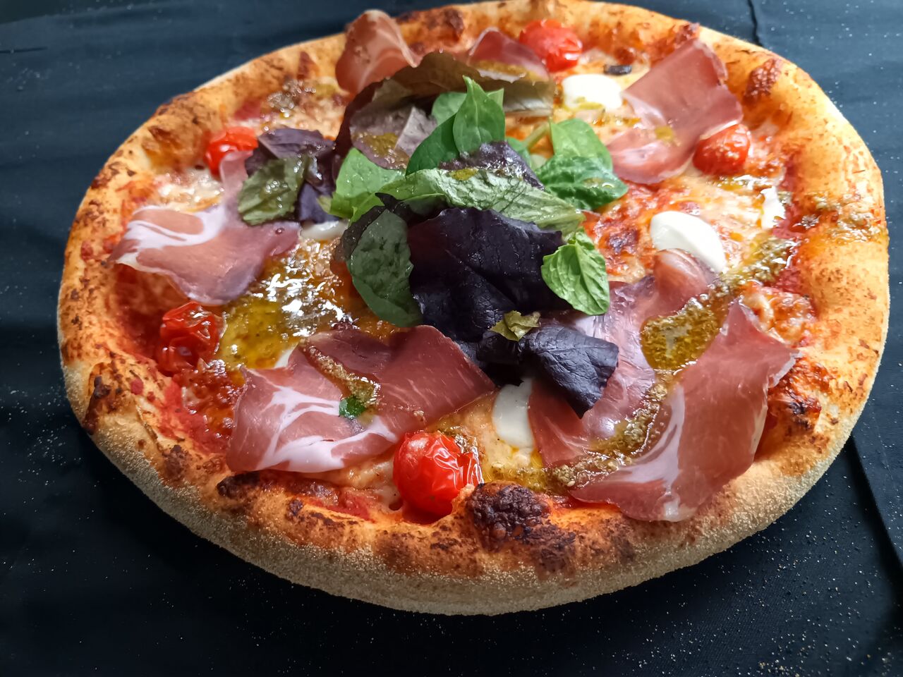 La Romaine: base tomate,coppa,billes de mozzarella,tomates cerises,mélange salade,pesto.16.00€