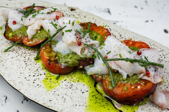 🍅 Tomate a la brasa, pesto, queso parmesano 🧀 y carpaccio de serviola 🐠 con su piel crujiente.