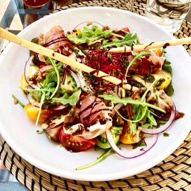 Burrata crémeuse, tomates colorées, jambon cru, roquette, vinaigrette au Pesto et crème de balsamique 