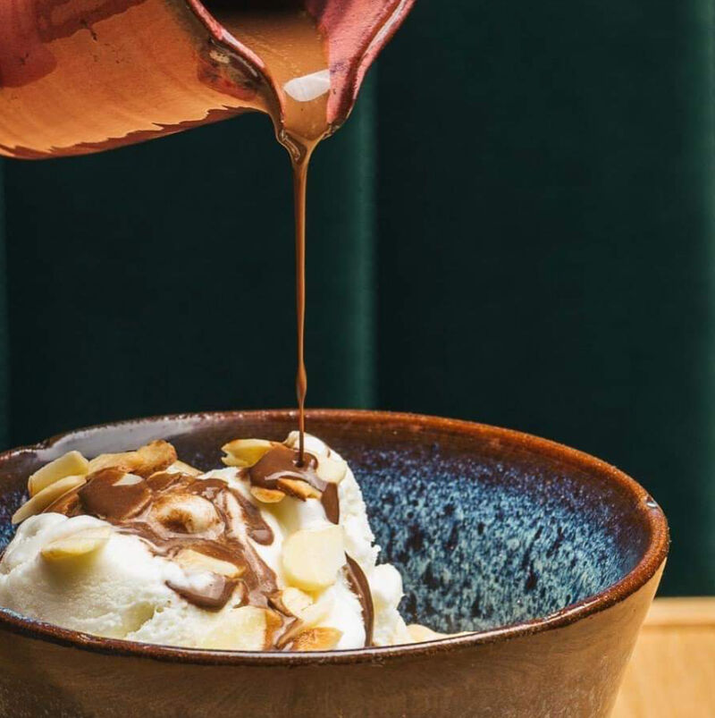 Gelado de nata com calda de chocolate e amêndoas laminadas.