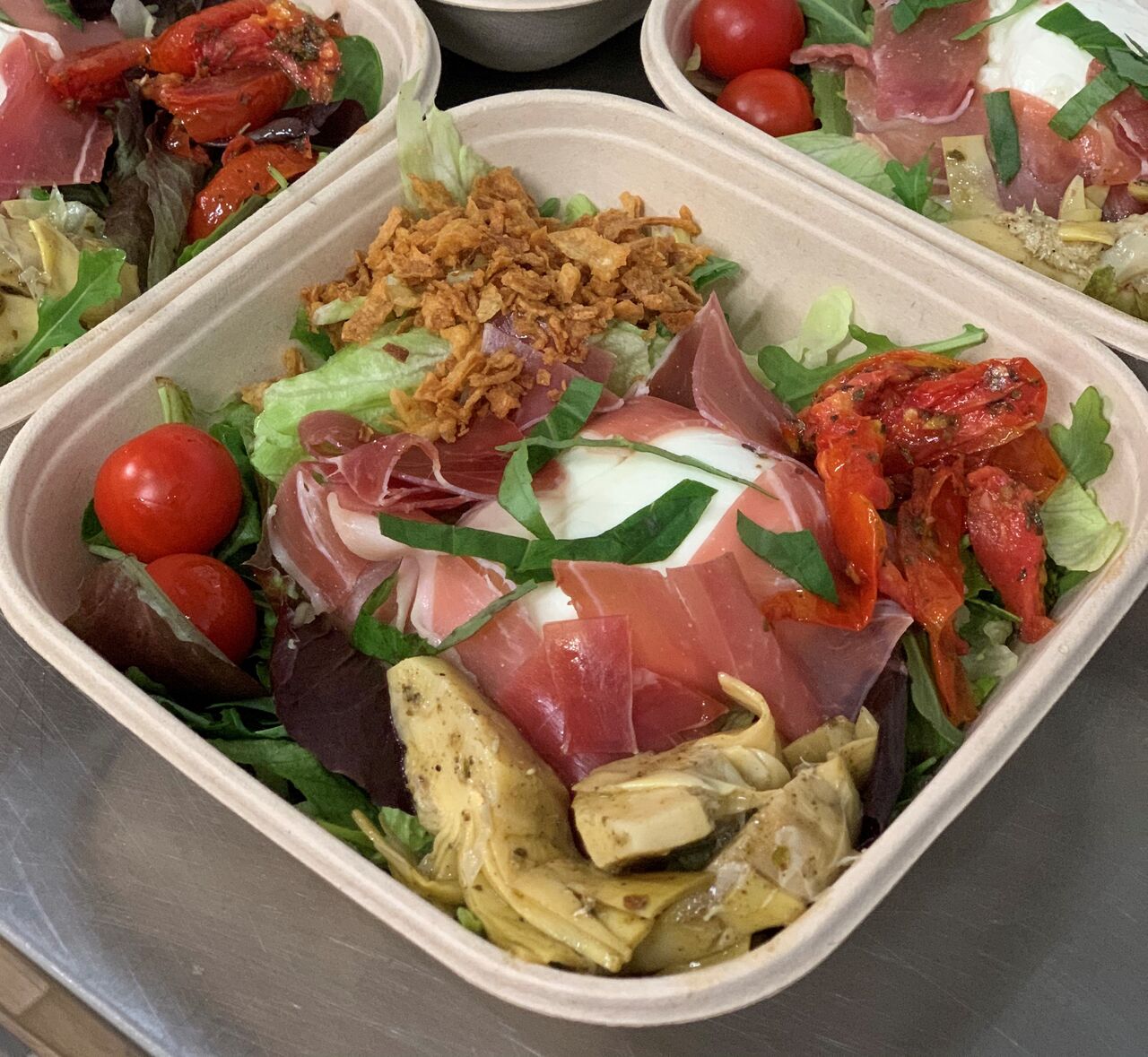 Iceberg et roquette, Mozzarella, jambon de Serrano, tomates cerises, tomates confites, cœurs d'artichaut à l'huile et oignons.