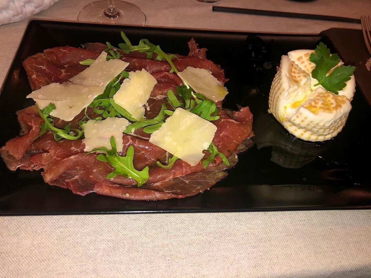 Carne salda cruda con scaglie di parmigiano, rucola e burrata