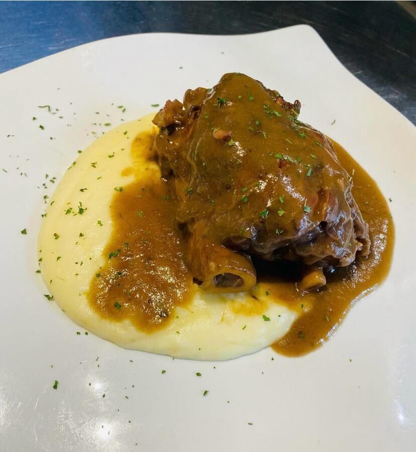 Codillo a baja temperatura en su salsa sobre pure de patatas.