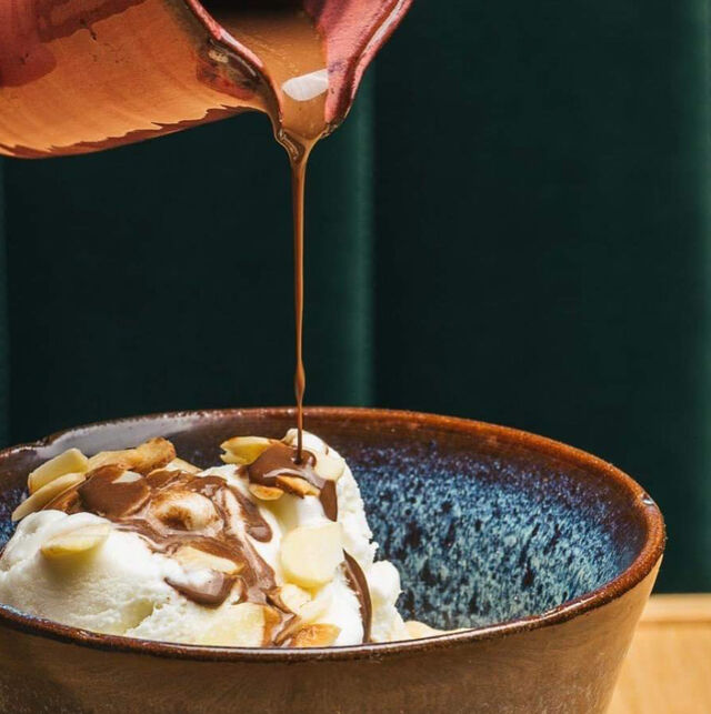 Gelado de nata com calda de chocolate e amêndoas laminadas.