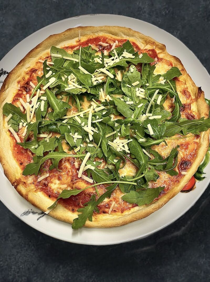 Probieren Sie einen Klassiker der italienischen Küche - unsere herzhafte Rucola-Pizza mit frisch gehobelten Parmigiano! 