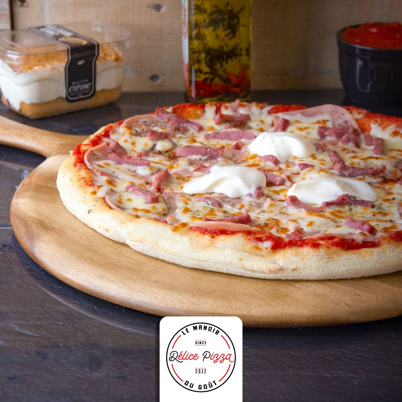 LA REINE : sauce tomate, jambon, mozzarella, lardons, 3 pointes de crème fraiche, origan