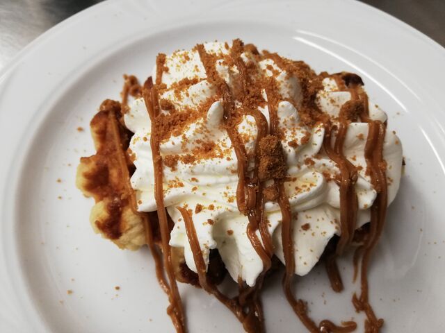 Gepimpte, verse suikerwafel met slagroom en speculaascrunch en speculaastopping.