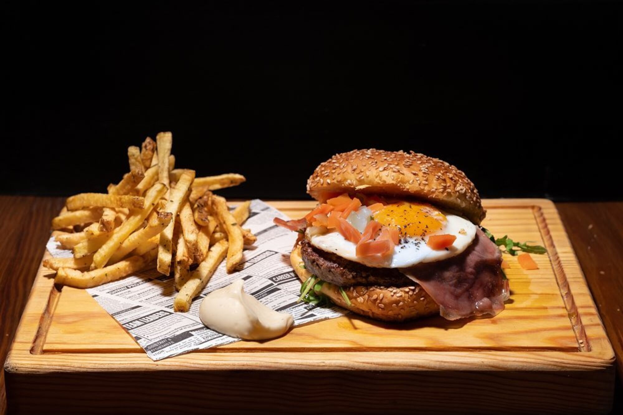 Hambúrguer da Ferraria com ovo estrelado, presunto e batatas, servido numa tábua