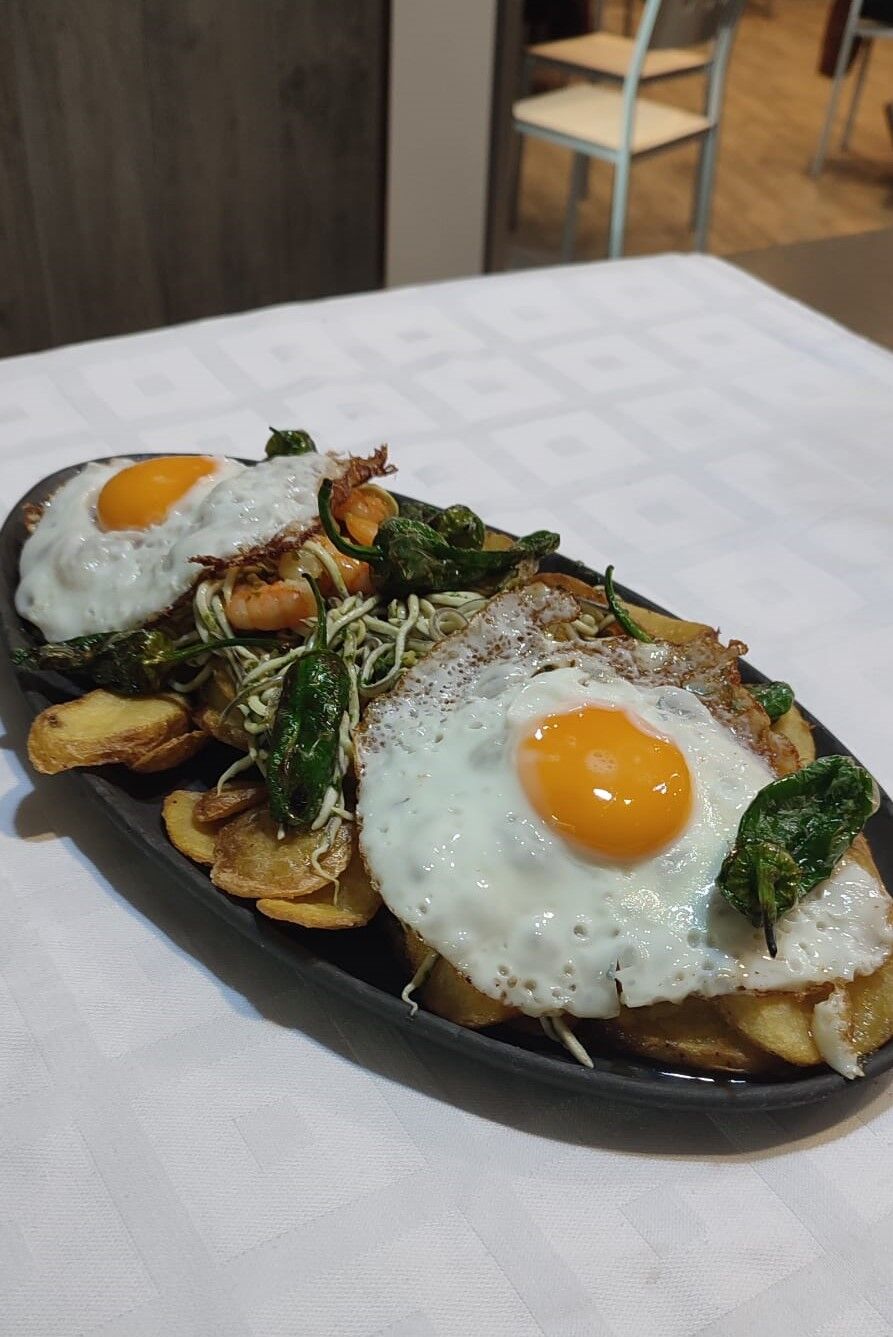 Huevos rotos con gulas y gambas